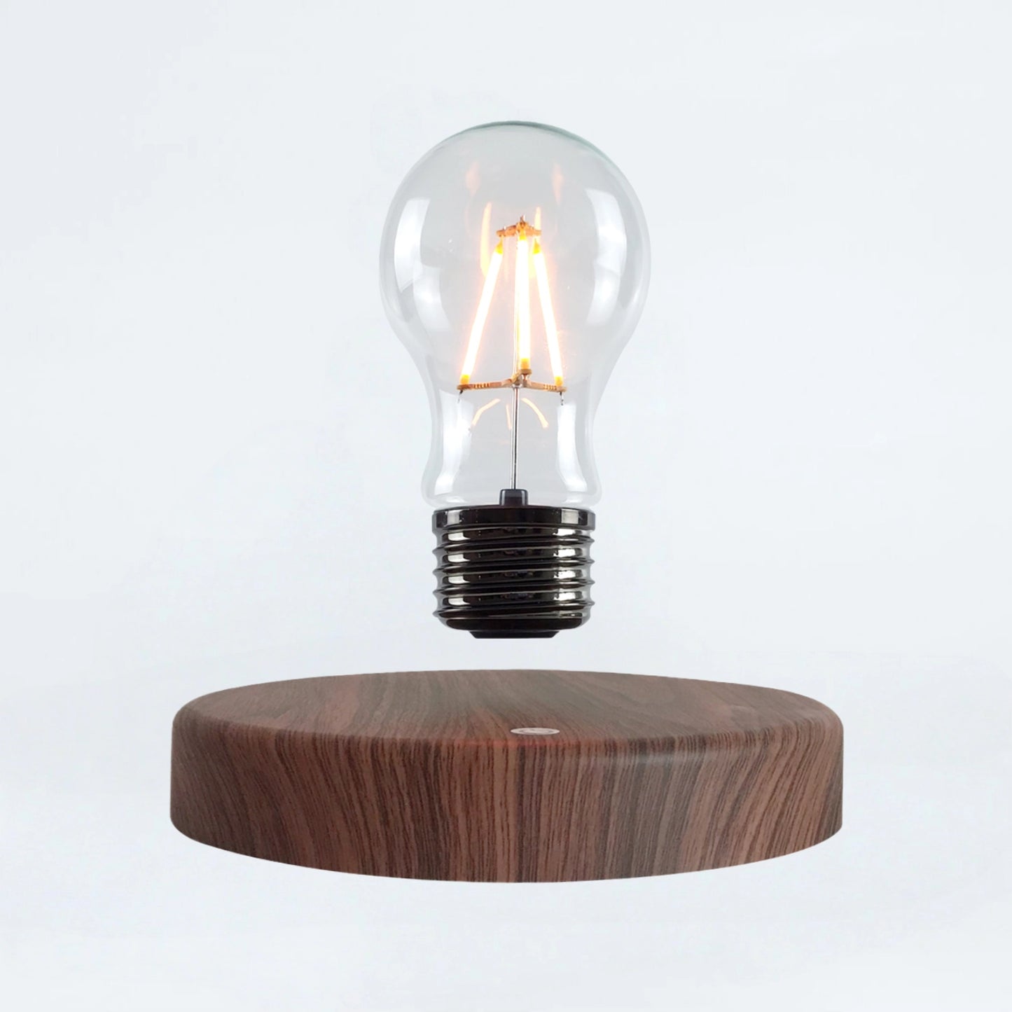Classic light bulb magnetic levitating lamp on wood base, white background