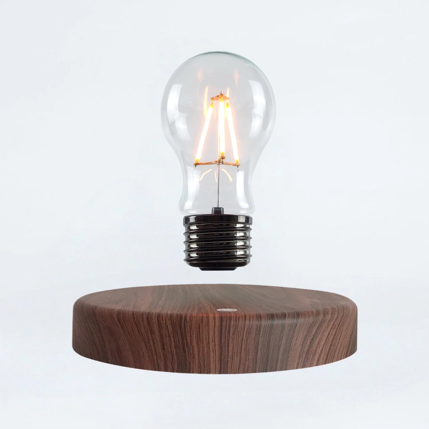 Classic light bulb magnetic levitating lamp on wood base, white background