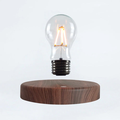 Classic light bulb magnetic levitating lamp on wood base, white background