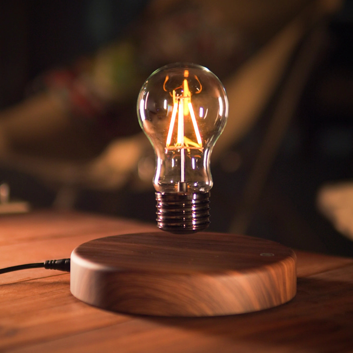 Classic light bulb magnetic levitating lamp glowing in warm ambient lighting on wooden base