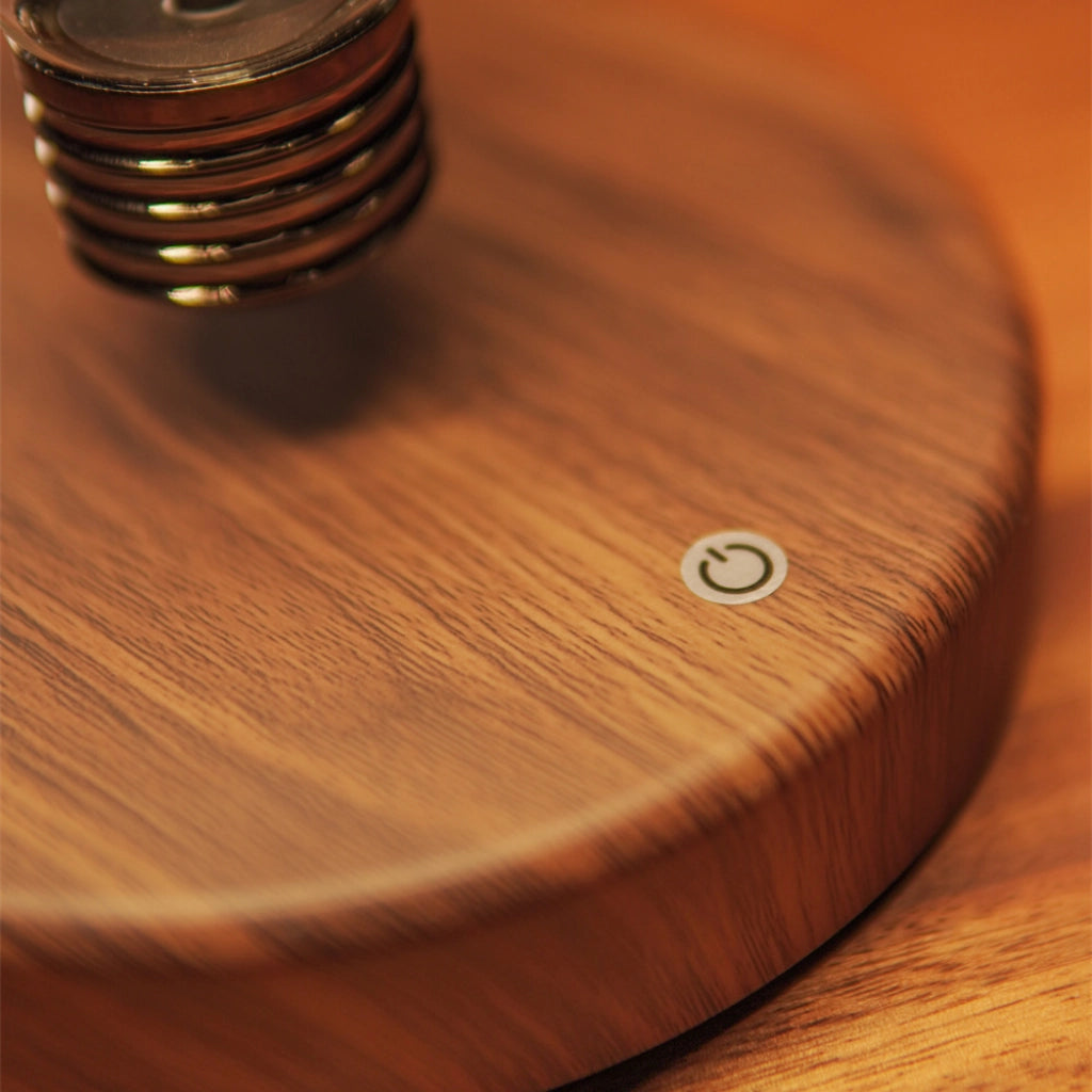 Close-up of wooden base and power button of classic light bulb magnetic levitating lamp
