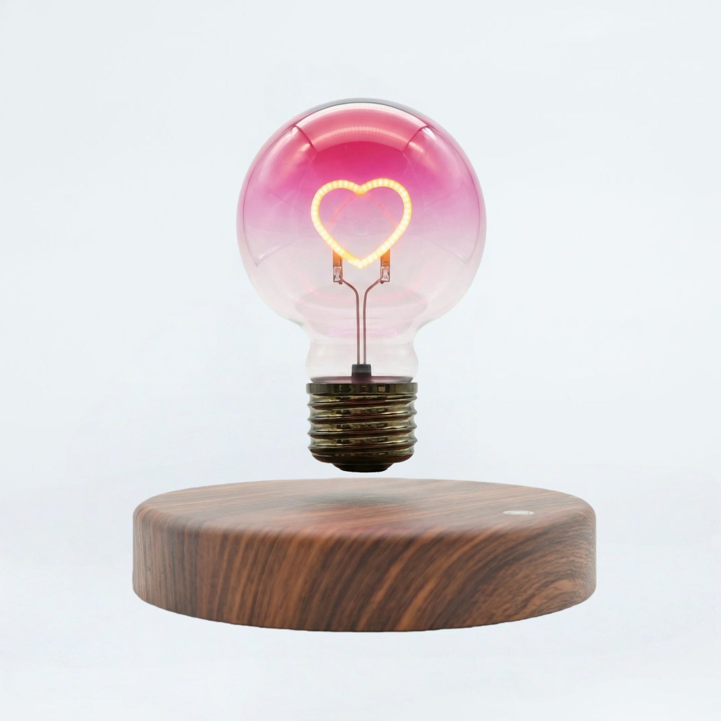 Floating heart light bulb magnetic levitating lamp on wooden base, white background