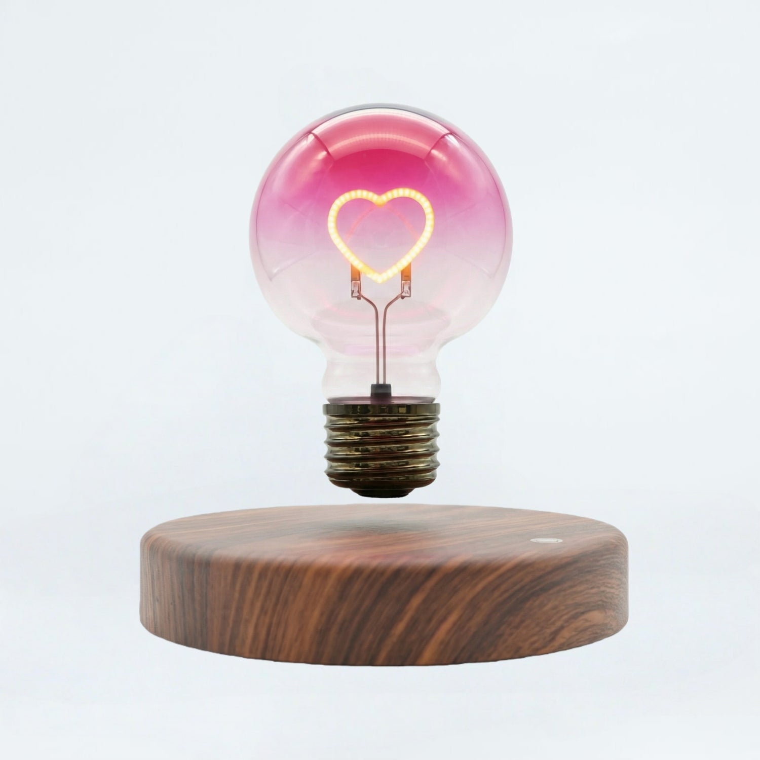 Floating heart light bulb magnetic levitating lamp on wooden base, white background