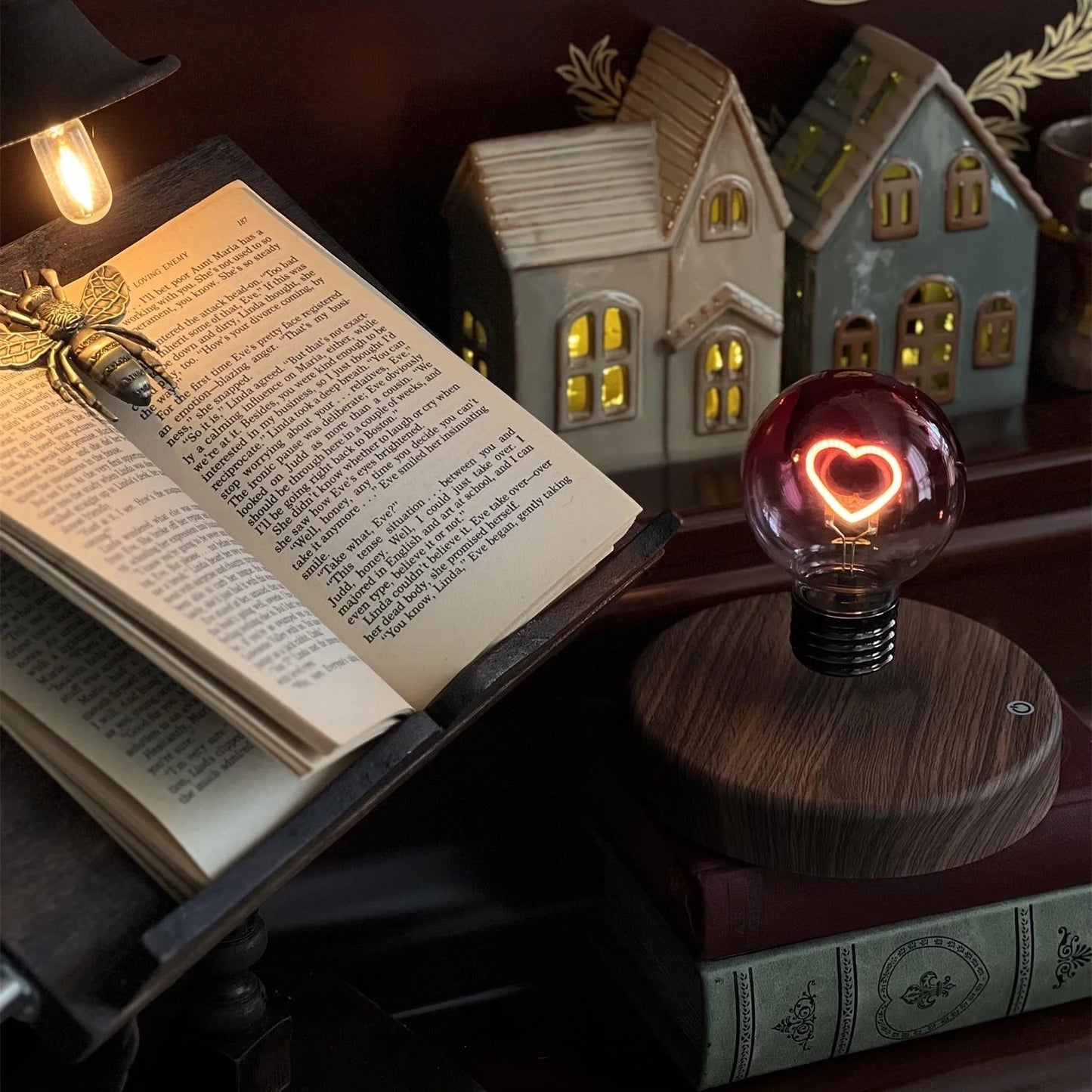 Heart light bulb magnetic levitating lamp on bedside table with books and houses