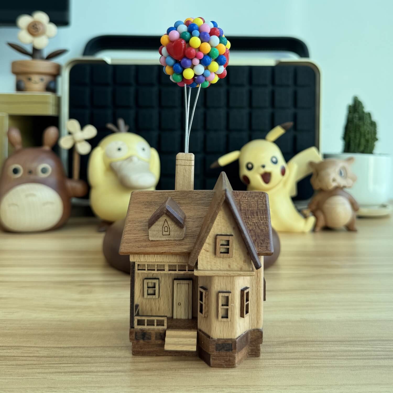  Levitating up house with colorful balloons displayed on a gaming desk setup with cute anime figures.