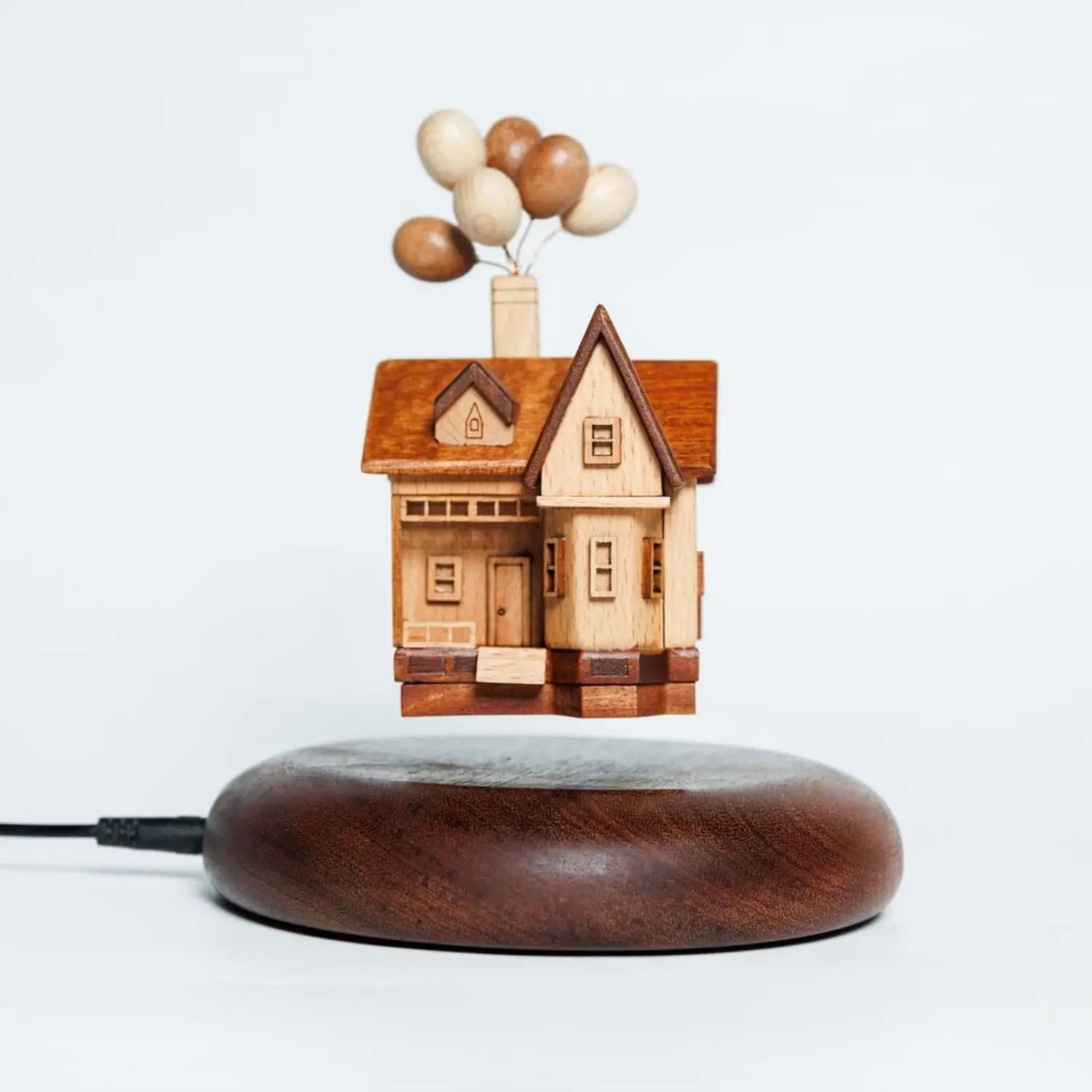 Main product shot of the handcrafted wooden balloon house floating above a magnetic walnut base.