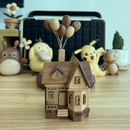 The all-wood version of the levitating balloon house displayed among anime collectibles on a wooden desk